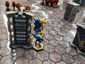 A close up shot of a Battletech map. A Hierofalcon is getting a rear armour shot on a Berserker, which is capturing an objective.